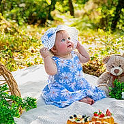 Shelby participe au concours pour gagner de l'argent avec cette photo : baby, child, blue_dress, sunhat, outdoor, picnic, blanket, teddy_bear, pastries, greenery, nature, cute, sitting, curious, summer, food, plate, flower_pattern, daylight, happy
