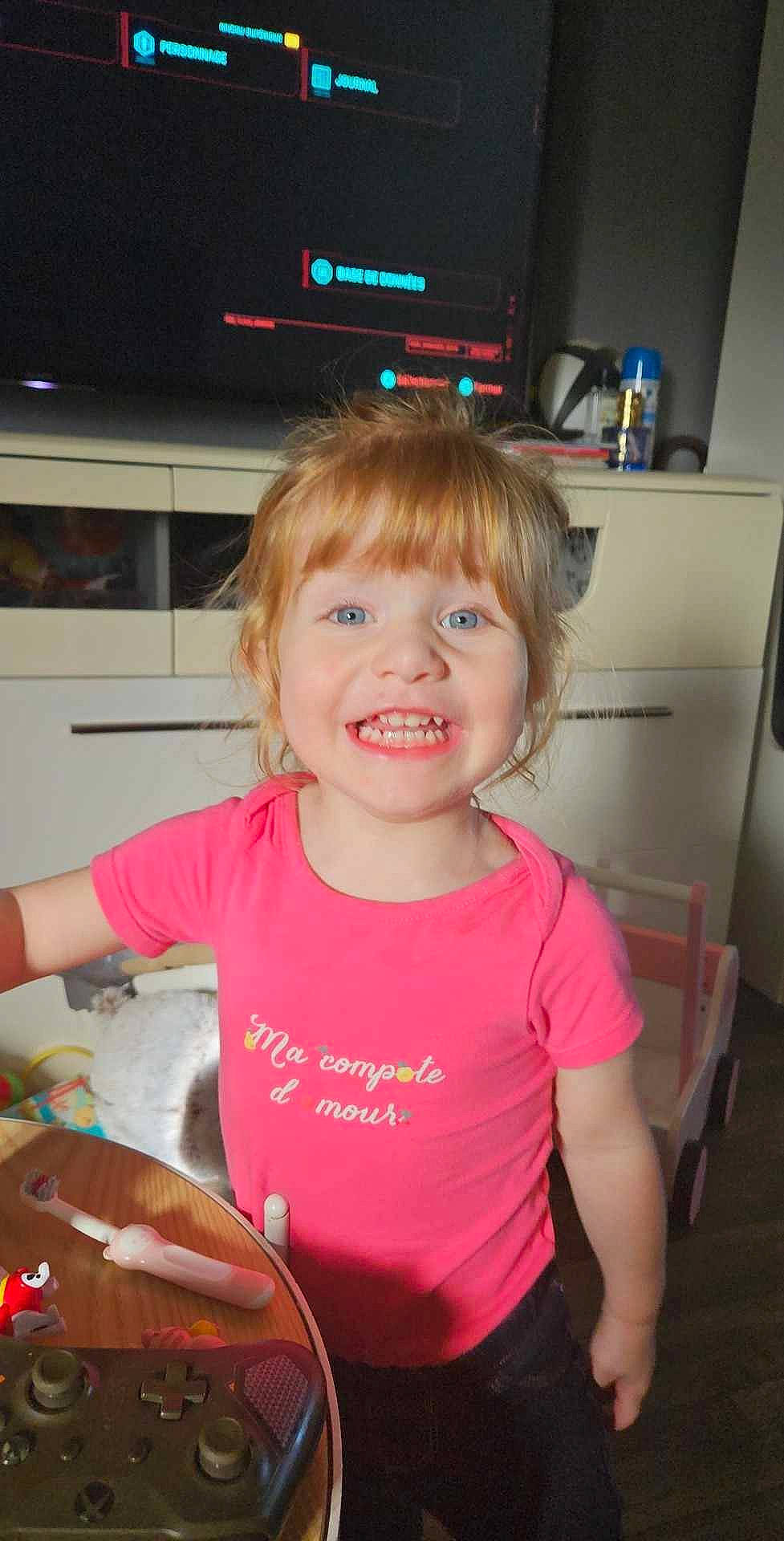 Emma participe au concours pour gagner de l'argent avec cette photo : bangs, blond, chair, cheek, child, chin, eyelash, fun, hair, hairstyle, happy, home_appliance, iris, joy, mammal, person, smile, standing, t_shirt, television