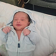 Lyam is registered to the contest to win money with this photo: baby, newborn, infant, hooded_jacket, blanket, pacifier, bed, smile, hands, face, pajamas, cute, indoor, pillow, stroller, soft_texture, zipper, cheeks, mattress, laying_down