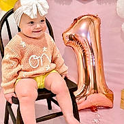 Charleigh is registered to the contest to win money with this photo: baby, toddler, child, bow_headband, white_bow, knitted_sweater, flower_detail, wooden_chair, rose_gold_balloon, number_one_balloon, pink_backdrop, birthday_party, celebration, smiling, sitting, legs, bare_feet, portrait, cute, party_decor