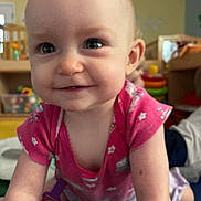 Jessie is registered to the contest to win money with this photo: baby, child, infant, crawling, pink_shirt, smiling, indoor, playroom, toys, colorful, floor, person, face, cute, young_child, happy, clothing, socks, background, furniture