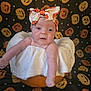 baby, infant, pumpkin, headband, halloween, costume, white_clothing, decorative_background, jack_o_lantern, orange, cute, portrait, child, holiday_theme, festive, smiling, indoors, face, celebration, seasonal