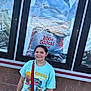 brick_wall, cartoon_character, casual_clothing, child, daylight, disney, glass, happy, lilo_and_stitch, movie_poster, outdoor, person, portrait, red_bag, reflection, smiling, standing, tshirt, urban, young