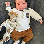 Enzo participe au concours pour gagner de l'argent avec cette photo : baby, infant, child, blanket, soft_toy, reindeer, knitted_toy, white_shirt, brown_pants, white_socks, lying_down, curious_expression, cute, indoor, portrait, face, hands, feet, cozy, comfortable