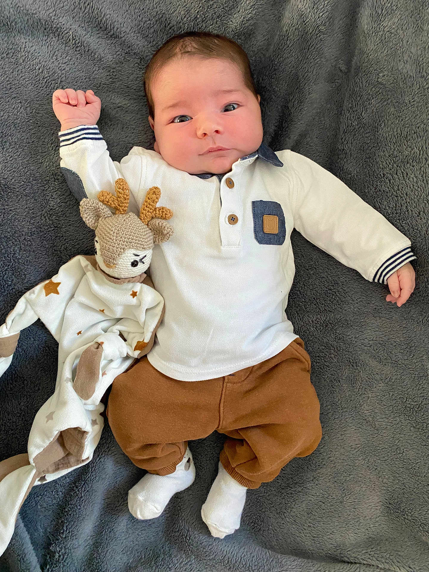 Enzo participe au concours pour gagner de l'argent avec cette photo : baby, infant, child, blanket, soft_toy, reindeer, knitted_toy, white_shirt, brown_pants, white_socks, lying_down, curious_expression, cute, indoor, portrait, face, hands, feet, cozy, comfortable