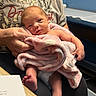 newborn, baby, infant, child, portrait, face, eyes, smiling, blanket, pink_blanket, adult, parent, holding, indoor, seated, chair, hospital, clothing, barefoot, family