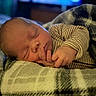 newborn, baby, sleeping, infant, portrait, face, closed_eyes, curled_up, hand, fingers, striped_clothing, onesie, blanket, fuzzy_blanket, cozy, indoors, soft_lighting, peaceful, resting, close_up