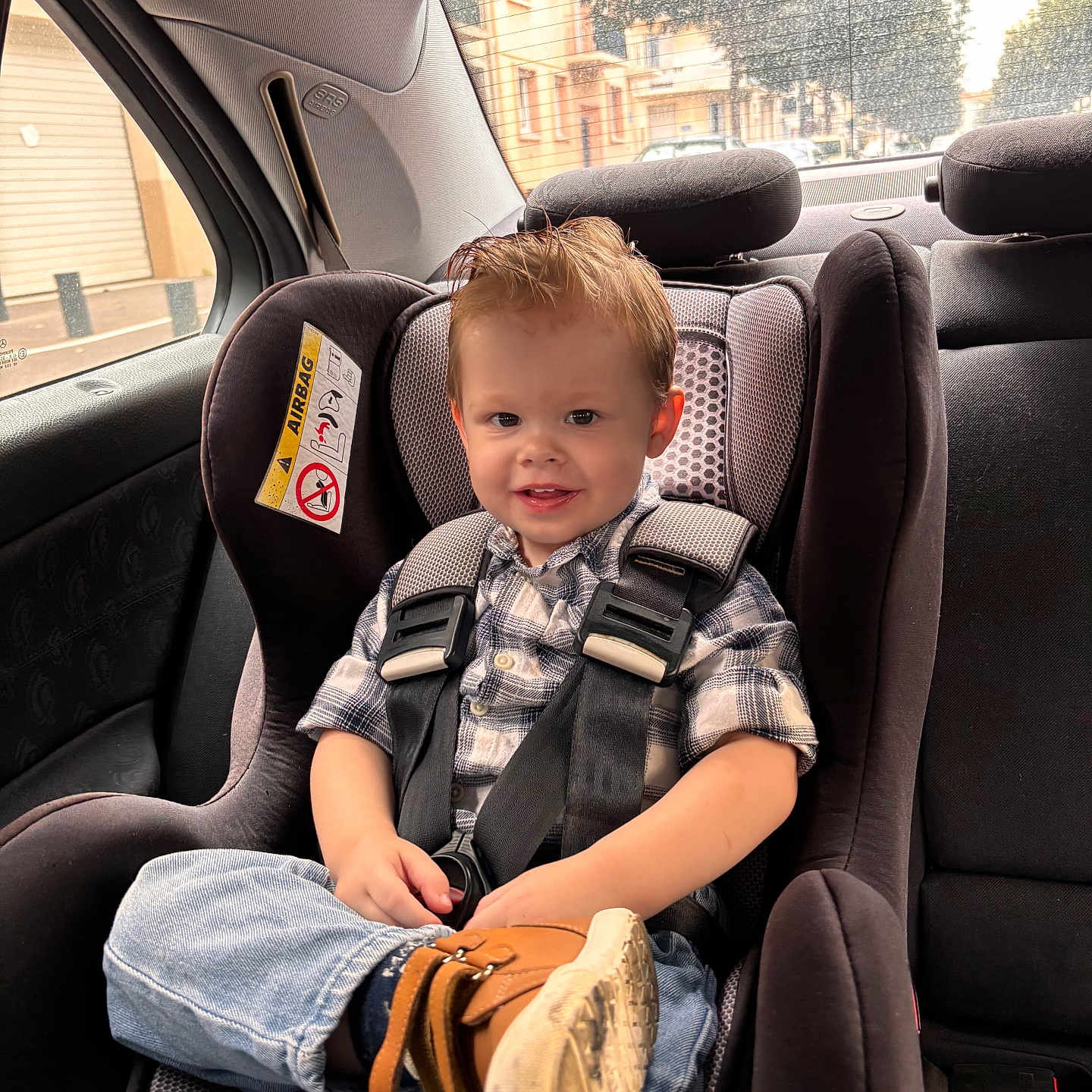 Tobias participe au concours pour gagner de l'argent avec cette photo : boot, car_interior, car_seat, casual_clothing, child, daylight, hair, happy, jeans, plaid_shirt, rain, safety, seat, seat_belt, smile, street, toddler, urban, vehicle, window