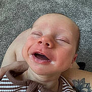 Riley-James is registered to the contest to win money with this photo: baby, smiling, infant, face, closed_eyes, striped_clothing, tattoo, arm, carpet, happy, mouth_open, person, skin, cute, newborn, portrait, child, young, indoors, human