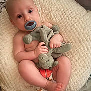 Riley-James is registered to the contest to win money with this photo: baby, infant, pacifier, stuffed_animal, blanket, soft_texture, cute, child, lying_down, bare_skin, toy, indoors, cozy, toddler, sleeping_area, comfort, small_hands, small_feet, head, face