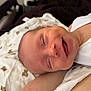 Riley-James is registered to the contest to win money with this photo: baby, smiling, infant, white_clothing, blanket, patterned_blanket, lying_down, happy, closed_eyes, mouth_open, skin, face, head, newborn, cozy, cute, child, portrait, indoors, resting