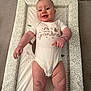 Riley-James is registered to the contest to win money with this photo: arm, baby, carpet, changing_mat, child, cute, face, floor, happy, indoor, infant, leaf_pattern, leg, onesie, pattern, person, pointing, skin, smile, text_on_clothing