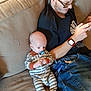 Kade joined the competition — help win amazing prizes! baby, beard, casual_clothing, cord, couch, curly_hair, glasses, indoor, infant, jeans, man, pacifier, person, playing, relaxing, seated, sofa, striped_pajamas, technology, watch