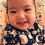 baby, smile, tongue, face, infant, onesie, patterned_clothing, stars, moon, zipper, blanket, floral_pattern, closeup, cheeks, happy, cute, child, portrait, sleepwear, indoors