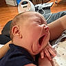 Luka is registered to the contest to win money with this photo: baby, yawning, infant, arms, person, indoor, floor, wooden_floor, furniture, blanket, clothing, skin, hand, face, head, sleepy, cozy, home, relaxing, closeup