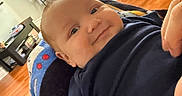 Luka joined the competition — help win amazing prizes! baby, smile, blanket, living_room, sofa, wooden_floor, window, table, chair, person, infant, face, cute, home_interior, cushion, arm, clothing, cozy, happy, indoor