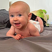 Autumn is registered to the contest to win money with this photo: baby, smiling, tummy, bed, diaper, blue_eyes, happy, infant, skin, head, person, young_child, indoors, pillow, blanket, cute, child, expression, face, lying_down