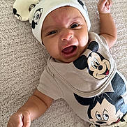 Adonis joined the competition — help win amazing prizes! baby, infant, smiling, mickey_mouse, hat, clothing, cute, happy, lying_down, carpet, child, portrait, raising_fist, funny_expression, soft_texture, cute_outfit, baby_fashion, indoor, adorable, closeup