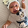 baby, infant, smiling, mickey_mouse, hat, clothing, cute, happy, lying_down, carpet, child, portrait, raising_fist, funny_expression, soft_texture, cute_outfit, baby_fashion, indoor, adorable, closeup