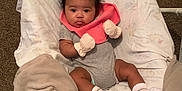 Zoie is registered to the contest to win money with this photo: baby, baby_seat, bib, blanket, carpet, child, clothing, comfort, cute, face, indoor, infant, mittens, onesie, person, portrait, relaxing, socks, soft_texture, young_child