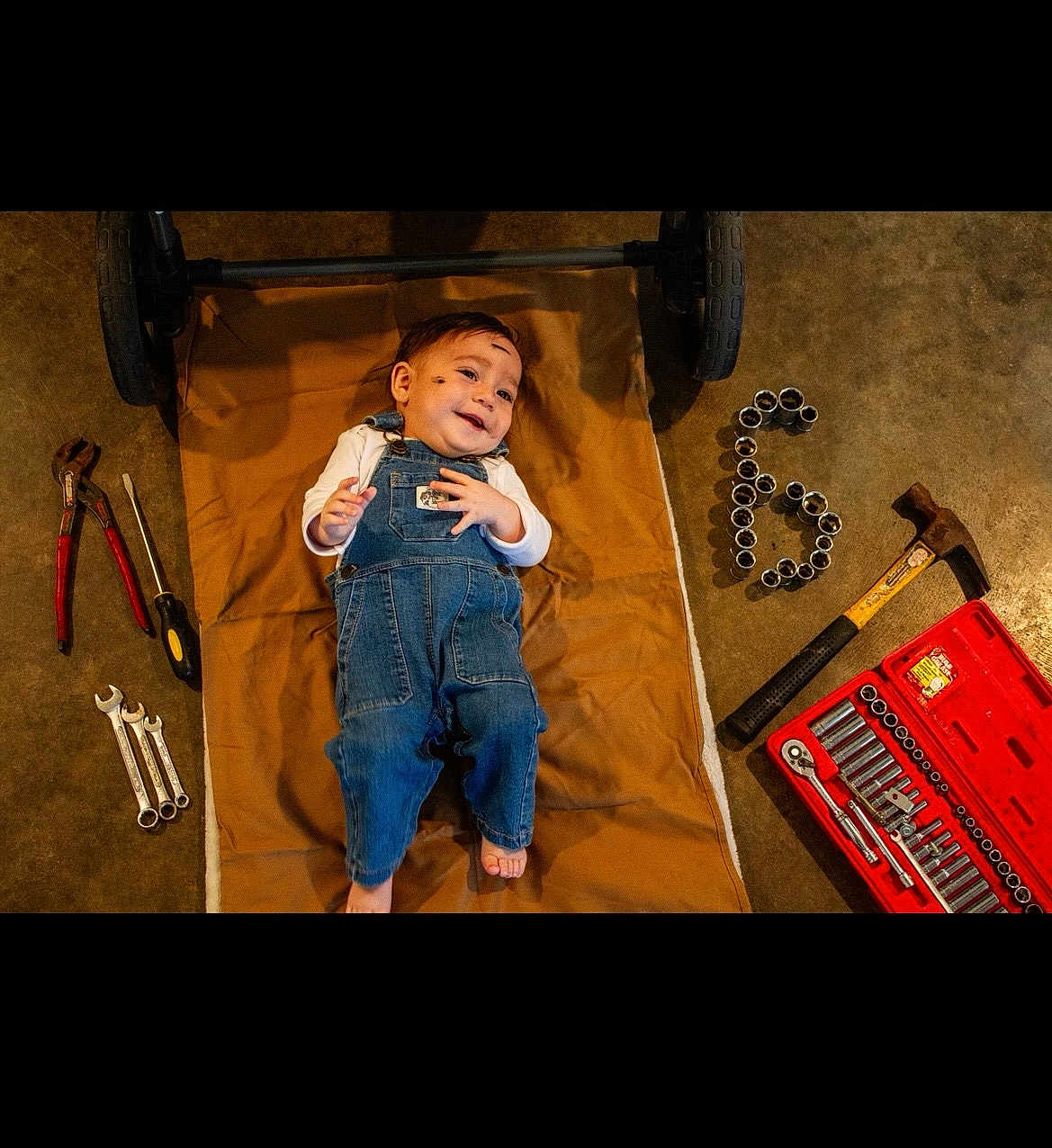 Oliver joined the competition — help win amazing prizes! baby, denim_overalls, tools, hammer, wrenches, toolbox, floor, mat, happy, smiling, child, workshop, mechanic, plush, indoor, person, footwearless, cute, portrait, equipment
