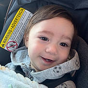 Oliver joined the competition — help win amazing prizes! baby, child, infant, smile, teeth, car_seat, pacifier, blanket, hoodie, soccer_pattern, safety_warning, strap, close_up, portrait, eyes, hair, window, cozy, happy, seat