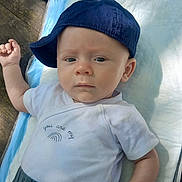 Simon participe au concours pour gagner de l'argent avec cette photo : baby, infant, child, cap, hat, white_clothing, onesie, outdoor, soft_surface, expression, face, blue_cap, lying_down, person, young_child, skin, hand, cute, daylight, closeup