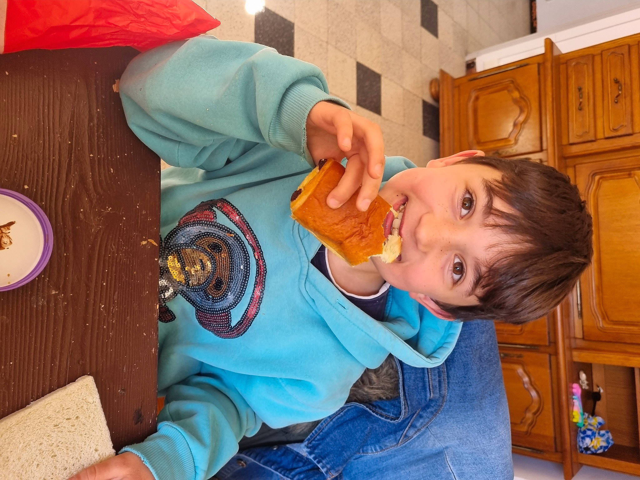 Erwan participe au concours pour gagner de l'argent avec cette photo : baby, baby_toddler_clothing, cabinetry, chair, child, clothing, cooking, elbow, fun, happy, joy, leisure, mouth, orange, person, play, room, sitting, smile, t_shirt