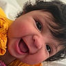 baby, blanket, cheerful, child, close_up, curly_hair, cute, expression, face, happy, indoors, infant, joyful, person, playful, portrait, smiling, soft, yellow_clothing, young