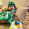 baby, birthday_cake, blanket, cake, celebration, child, colorful, crown, curly_hair, cute, doll, festive, food, green_dress, happy, indoor, person, smile, toddler, toy