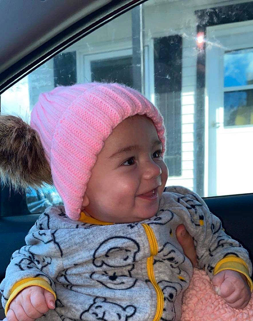 Rosalie a rejoint le concours — aidez-le/la à gagner de superbes lots ! baby, baby_toddler_clothing, cap, cheek, child, facial_expression, finger, fun, happy, headwear, joy, leisure, mammal, mouth, nose, person, sitting, skin, sleeve, smile