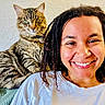 Sonic is registered to the contest to win money with this photo: person, smiling, cat, tabby_cat, heterochromia, indoor, couch, textured_wall, curly_hair, white_tshirt, pet, animal, happy, relaxed, portrait, feline, domestic_cat, companion, closeup, friendship