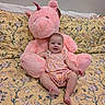 Madison is registered to the contest to win money with this photo: baby, bed, child, cozy, cuddly, cute, floral_pattern, happy, indoors, infant, person, pink, plush_unicorn, portrait, romper, sitting, smiling, soft_toy, stuffed_animal, yellow_bedspread