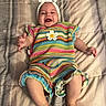 baby, smiling, colorful_clothing, headband, blanket, happy, infant, striped_outfit, crawling, cute, child, lying_down, portrait, indoors, soft_lighting, cheerful, young_child, skin, hands, feet