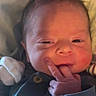 Edward is registered to the contest to win money with this photo: baby, button, child, close_up, clothing, cozy, eyes, face, family_photo, finger, hair, indoors, infant, mouth, newborn, onesie, portrait, seated, smiling, warm_lighting