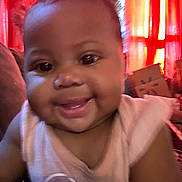 Kaliyajae is registered to the contest to win money with this photo: baby, background, candid, cheeks, child, closeup, clothing, curtains, face, happy, human, indoors, infant, person, portrait, red, smiling, soft_focus, toddler, warm_lighting