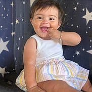 Souline is registered to the contest to win money with this photo: baby, child, smiling, happy, sitting, tank_top, striped_skirt, barefoot, bracelet, star_pattern, couch, indoor, cute, fingers_in_mouth, young_child, portrait, infant, playful, joyful, closeup