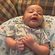 Dillon joined the competition — help win amazing prizes! baby, infant, child, smiling, happy, portrait, close_up, sitting, reclining, couch, cushion, pillow, plaid, indoor, home, gray_shirt, clothing, hands, face, photography