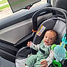 Dillon joined the competition — help win amazing prizes! baby, child, infant, car, car_seat, vehicle, portrait, smiling, happy, sitting, toy, plush_toy, green_clothing, overalls, socks, window, sunlight, road_trip, interior, family