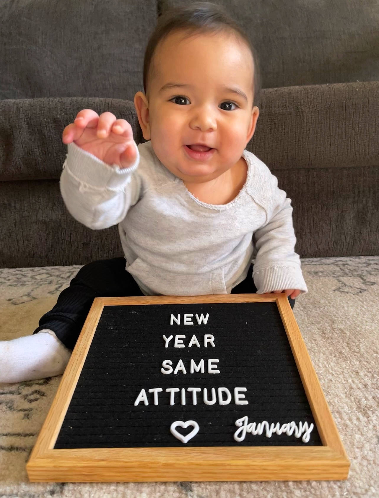 Taveien is registered to the contest to win money with this photo: arm, baby, baby_toddler_clothing, blackboard, cheek, child, face, finger, flooring, font, gesture, happy, hardwood, joy, person, product, sleeve, smile, t_shirt, thumb