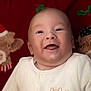 baby, child, closeup, cozy, cute, eyes, face, festive, happy, head, holiday_theme, indoors, infant, mouth, plush_toy, portrait, red_background, skin, smiling, white_clothing