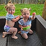 Dani And Peyton is registered to the contest to win money with this photo: toddler, child, watermelon, outdoor, grass, fence, sofa, wicker, matching_clothes, pigtails, summer, snack, barefoot, cute, two_children, greenery, playful, portrait, casual, happy