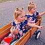 Dani And Peyton is registered to the contest to win money with this photo: toddler, child, wagon, wood, doll, matching_outfits, pony_tails, outdoor, asphalt, grass, cemetery, head, person, play, toy, pink, blue, flower_pattern, cute, happy