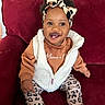 baby, child, clothing, couch, cozy, cute, fashion, footwear, happy, headband, indoors, leopard_print, pants, person, portrait, red_couch, sitting, smiling, toddler, vest
