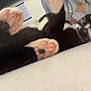 cat, black_and_white_cat, paws, pink_paws, lying_down, curious, indoor, person, grey_shirt, text_on_shirt, bed, white_bed, close_up, pet, animal, feline, whiskers, cute, relaxed, candid