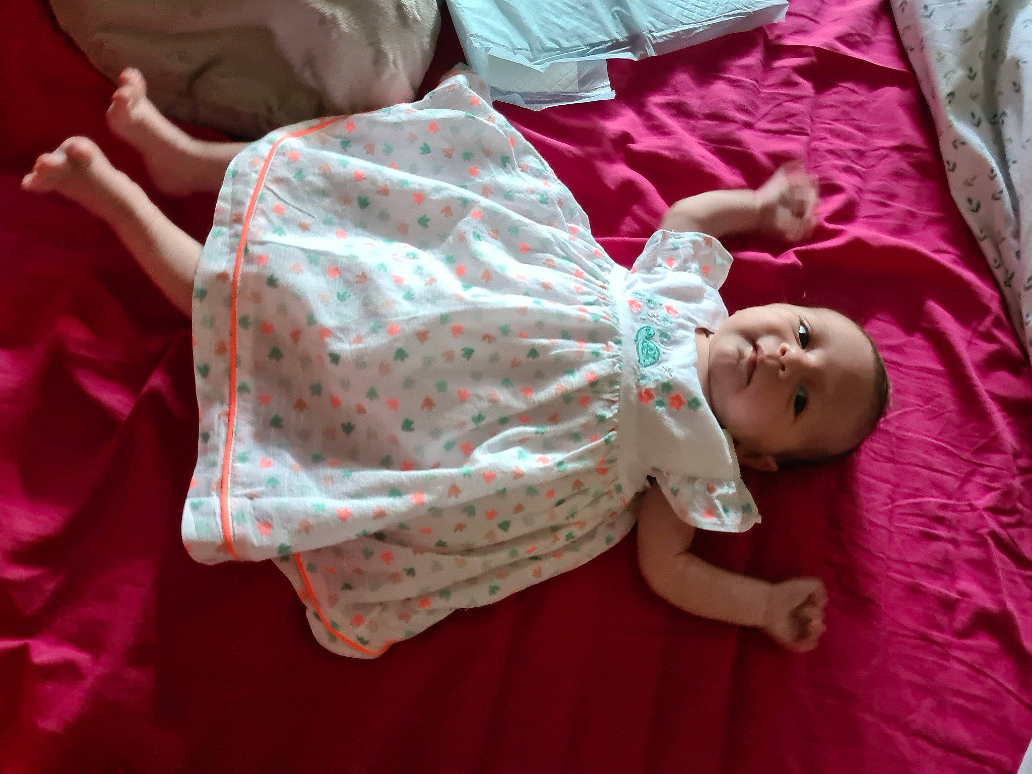 Ana participe au concours pour gagner de l'argent avec cette photo : baby, baby_products, baby_toddler_clothing, bedding, cheek, child, comfort, dress, linens, magenta, pattern, person, pink, purple, room, sitting, skin, sleeve, t_shirt, toddler