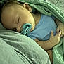 baby, sleeping, pacifier, blanket, blue_onesie, infant, peaceful, cozy, close_up, child, resting, soft_texture, cute, newborn, indoor, portrait, relaxed, hand, head, skin