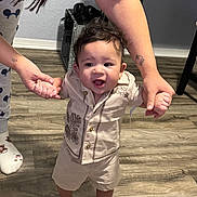 Adrian is registered to the contest to win money with this photo: toddler, child, baby, walking, hands, adult, indoor, floor, wooden_floor, clothing, shorts, shirt, smile, happy, person, footwear, tattoo, flooring, home, helping