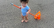 Adrian joined the competition — help win amazing prizes! asphalt, barefoot, blue_onesie, casual, child, curious, curly_hair, cute, daylight, orange_shovel, outdoor, parking_lot, play, single_child, small_person, standing, summer, toddler, toy, young_child