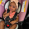 baby, child, car_seat, headband, smile, infant, safety_harness, cute, pink, clothing, white_socks, seat_belt, portrait, happy, indoor, person, car, baby_girl, fashion, accessory